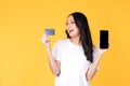 Portrait Asian happy young girl wearing white t-shirt happy smile and showing plastic credit card while holding mobile phone Royalty Free Stock Photo
