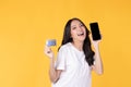 Portrait Asian happy young girl wearing white t-shirt happy smile and showing plastic credit card while holding mobile phone Royalty Free Stock Photo