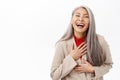 Portrait of asian lady in business suit looking healthy and happy, laughing and smiling, standing over white studio Royalty Free Stock Photo