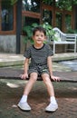 Portrait of Asian little boy kid sitting on wood bench in the garden Royalty Free Stock Photo