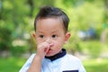 Portrait of Asian little child feeling itchy on his nose in the garden. Close-up kid scratching his nose outdoor Royalty Free Stock Photo