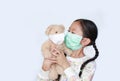 Portrait asian little child girl holding teddy bear with wearing medical protective mask together on white background Royalty Free Stock Photo