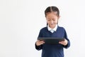 Portrait of asian little child girl in school uniform using tablet isolated on white background. Studio shot Royalty Free Stock Photo