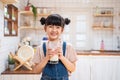 Portrait of Asian little cute kid holding a cup of milk in kitchen in house. Young preschool child girl or daughter stay home with