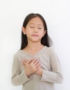 Portrait of Asian little girl closed eyes and holding hands on heart gesture of love. Kid place arms on chest isolated on white