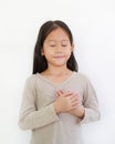 Portrait of Asian little girl closed eyes and holding hands on heart gesture of love. Kid place arms on chest isolated on white