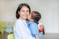 Portrait of Asian little girl kissing her happy mom and hugging on Mother`s day in thailand. Royalty Free Stock Photo