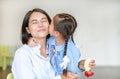 Portrait of Asian little girl kissing her happy mom and hugging on Mother`s day in thailand. Kid Pay respect. Royalty Free Stock Photo