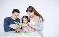 Portrait of asian little girl playing tree blocks with family mother father over white background.