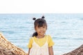 Portrait of an Asian little girl standing smile and looking camera by the sea while traveling. Royalty Free Stock Photo