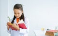 Portrait Asian little girl wearing white ground uniform, studying Science in class room at school, smiling, reading books, report Royalty Free Stock Photo