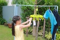 Portrait asian little kid girl putting clothespin and hangs socks to dry a clothes. Kid doing laundry in the garden