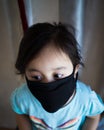 Portrait of asian Little toddler girl wearing reusable black fabric mask for protection from Coronavirus and Covid-19. Copy space Royalty Free Stock Photo