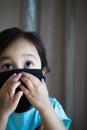 Portrait of asian Little toddler girl wearing reusable black fabric mask for protection from Coronavirus and Covid-19. Copy space Royalty Free Stock Photo