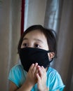 Portrait of asian Little toddler girl wearing reusable black fabric mask for protection from Coronavirus and Covid-19. Copy space Royalty Free Stock Photo