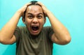 Portrait of an Asian Malay man with brown shirt screaming loudly, shocked face expression and holding head with two hands gesture. Royalty Free Stock Photo