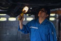 Portrait of asian male car mechanic performing car checking and maintenace service at garage and car maintenance service station Royalty Free Stock Photo