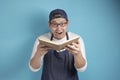 Portrait of Asian male chef reading book of recipes, finding secret recipe