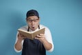 Portrait of Asian male chef reading book of recipes, finding secret recipe