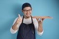 Asian Male Chef or Waiter Shows Empty Wooden Plate, Presenting Something, Copy Space Royalty Free Stock Photo