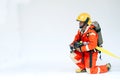 An Asian male firefighter in red protective uniform, mask and helmet with fire extinguisher sitting on white background. Royalty Free Stock Photo