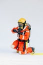 An Asian male firefighter in red protective uniform, mask and helmet with fire extinguisher sitting on white background. Royalty Free Stock Photo