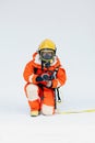 An Asian male firefighter in red protective uniform, mask and helmet with fire extinguisher sitting on white background. Royalty Free Stock Photo