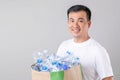 Portrait Asian man holding many empty clear old water bottle. Studio shot on grey background Royalty Free Stock Photo