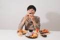 Portrait of asian man sitting and snacking donuts isolated over