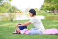 Portrait of Asian mother doing baby yoga for her son on green lawn in the nature garden outdoor Royalty Free Stock Photo