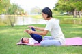 Portrait of Asian mother doing baby yoga for her son on green lawn in the nature garden outdoor Royalty Free Stock Photo