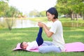 Portrait of Asian mother doing baby yoga for her son on green lawn in the nature garden outdoor Royalty Free Stock Photo