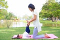 Portrait of Asian mother doing baby yoga for her son on green lawn in the nature garden outdoor Royalty Free Stock Photo