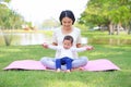 Portrait of Asian mother doing exercise for her son on green lawn in the nature garden outdoor Royalty Free Stock Photo