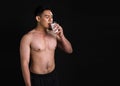 Portrait of asian muscular man standing and drinking milk on black background Royalty Free Stock Photo