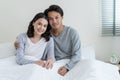 Portrait of Asian new marriage couple laying on bed and look at camera. Attractive beautiful young man and woman in pajamas enjoy Royalty Free Stock Photo