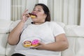 Asian overweight Asian woman enjoying her donuts at home