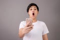 Portrait of an Asian person whose face was shocked by something on their smartphone