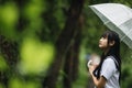 Portrait of Asian school girl walking with umbrella at nature walkway on raining Royalty Free Stock Photo