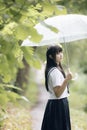 Portrait of Asian school girl walking with umbrella at nature walkway on raining Royalty Free Stock Photo