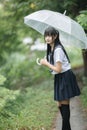 Portrait of Asian school girl walking with umbrella at nature walkway on raining Royalty Free Stock Photo