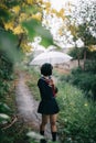 Portrait of Asian school girl walking with umbrella at nature walkway Royalty Free Stock Photo