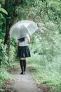 Portrait of Asian school girl walking with umbrella at nature walkway on raining Royalty Free Stock Photo