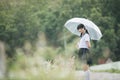 Portrait of Asian school girl walking with umbrella at nature walkway on raining Royalty Free Stock Photo