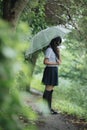 Portrait of Asian school girl walking with umbrella at nature walkway on raining Royalty Free Stock Photo