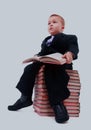 Portrait of asian schoolboy holding a book and sitting on a stack of books isolated on white. Royalty Free Stock Photo