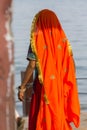 Portrait of Asian senior beautiful woman wearing traditional orange Indian dress sari. Near the beach, from behind Royalty Free Stock Photo