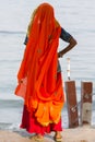 Portrait of Asian senior beautiful woman wearing traditional orange Indian dress sari. Near the beach, from behind Royalty Free Stock Photo