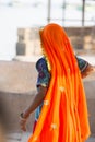 Portrait of Asian senior beautiful woman wearing traditional orange Indian dress sari. Near the beach, from behind Royalty Free Stock Photo