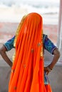 Portrait of Asian senior beautiful woman wearing traditional orange Indian dress sari. Near the beach, from behind Royalty Free Stock Photo